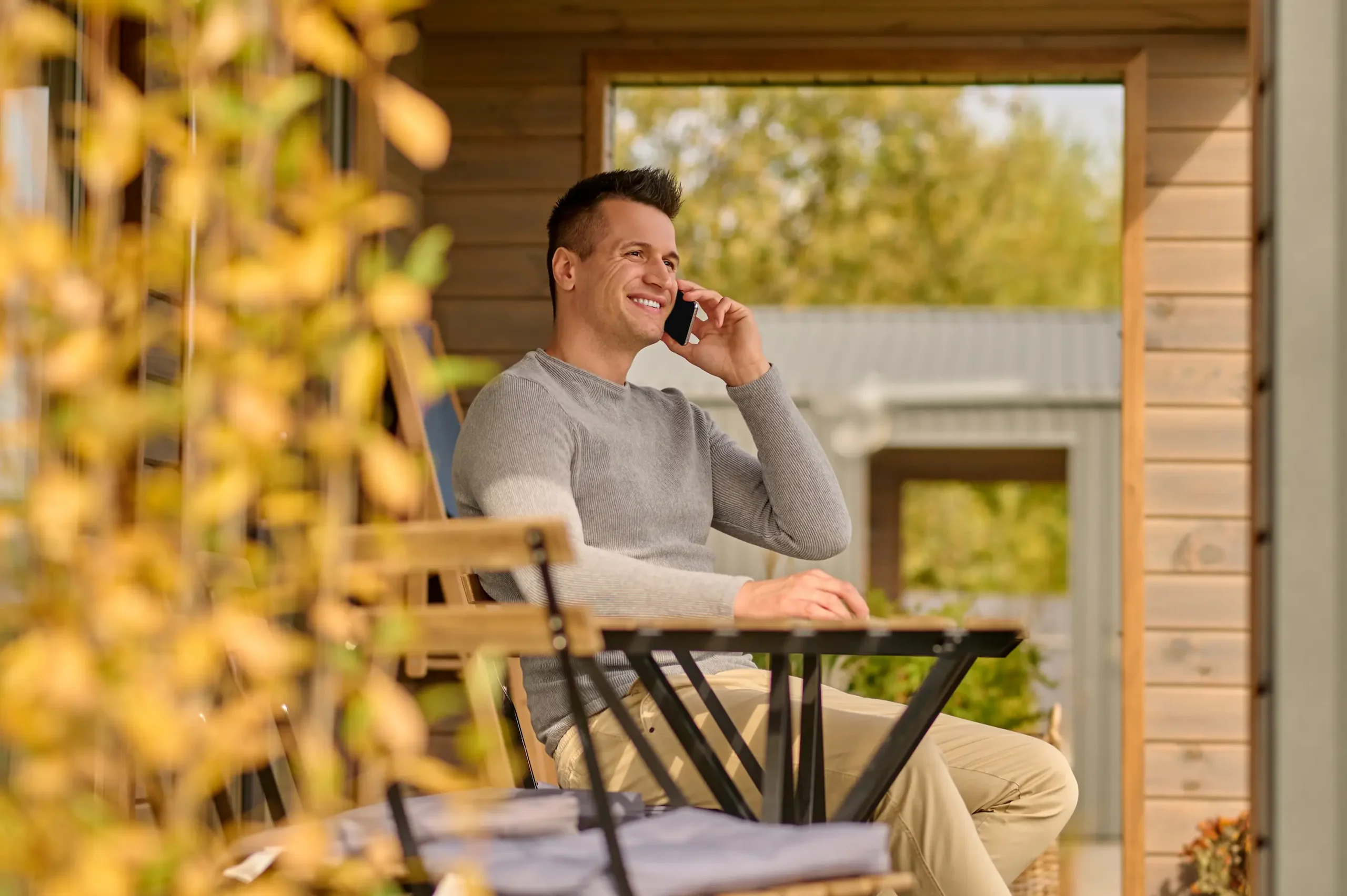 Man talking on a smartphone while sitting on an open terrace, representing the flexibility of securing Self-Employed Mortgages.